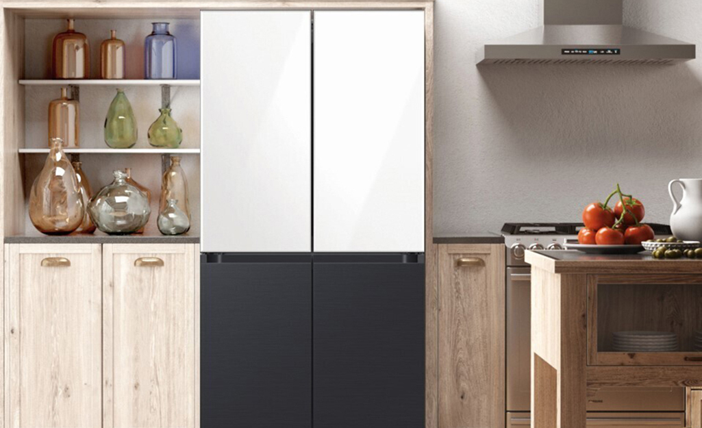A multi-colored refrigerator in a kitchen with pine cabinets.