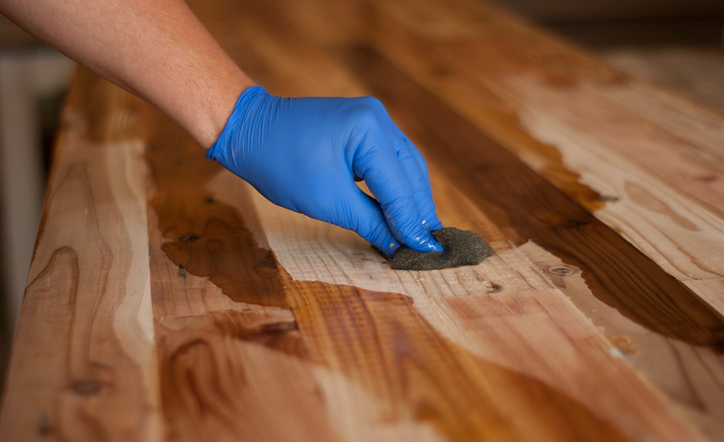 A person stains a butcher block countertop.