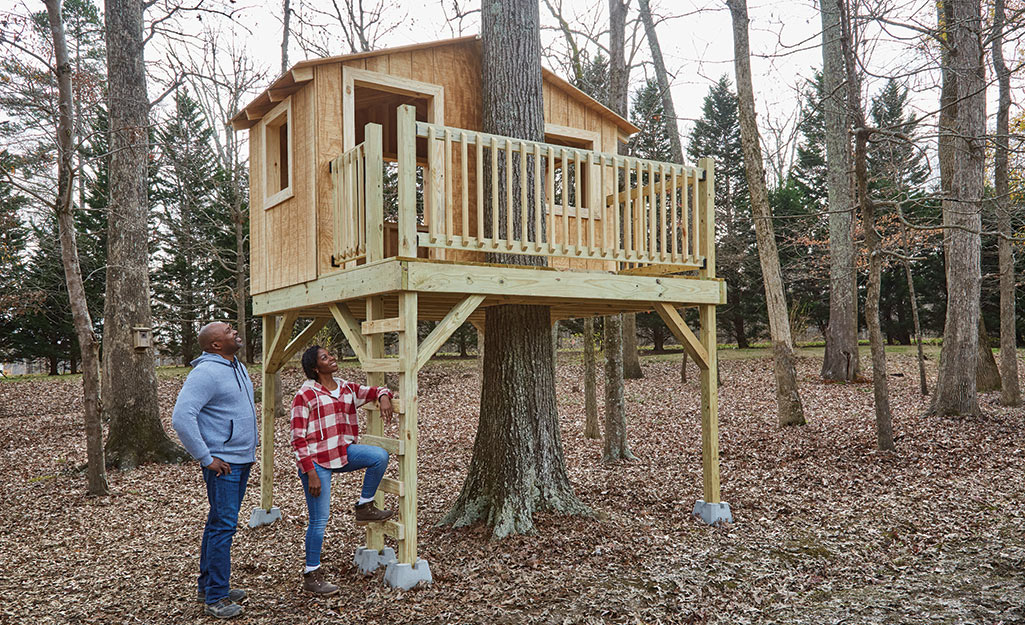 A couple admires their finished treehouse. 