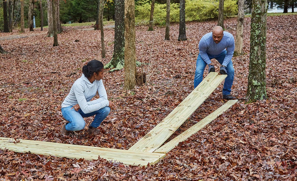 A man and woman lay out decking boards to determine the direction.