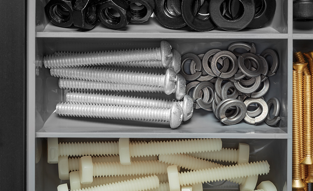Galvanized machine screws and lock washers are stacked in a hardware organizer.