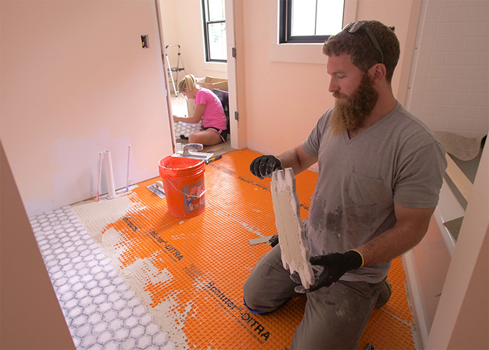 Man installing bathroom flooring.