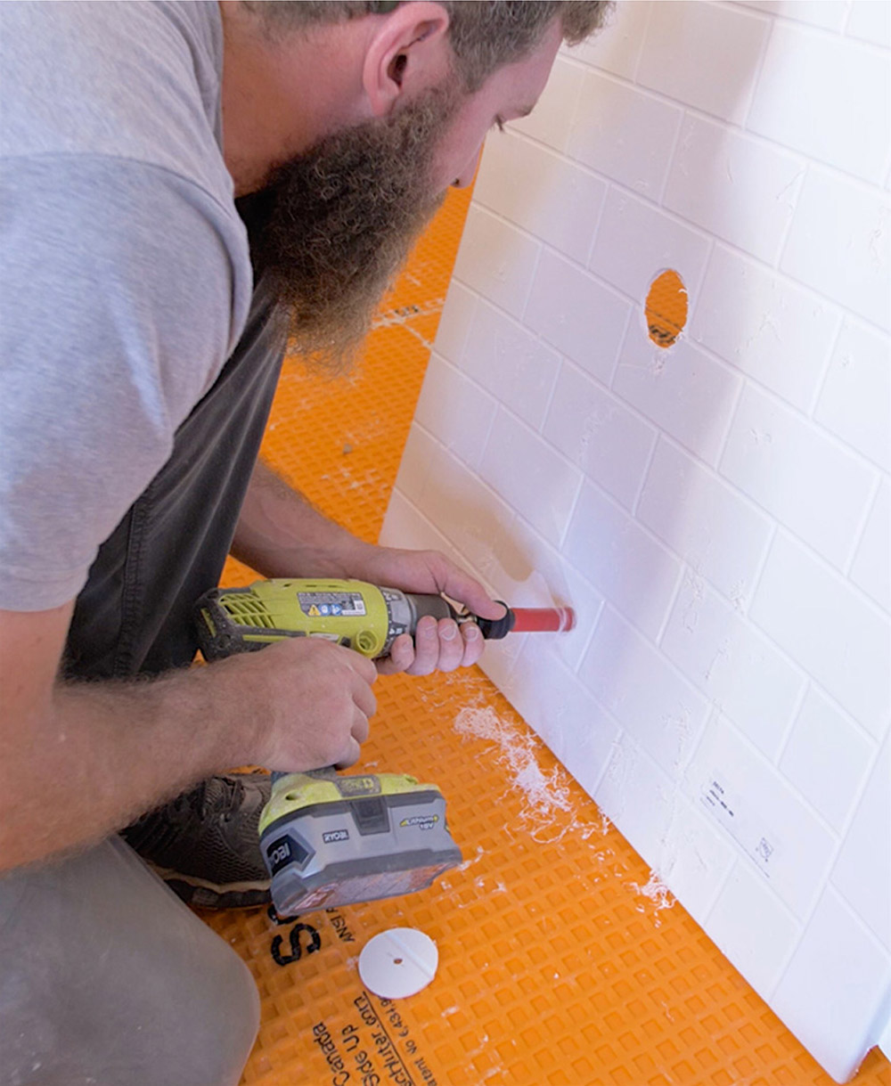 A man drilling a hole in a white wall.