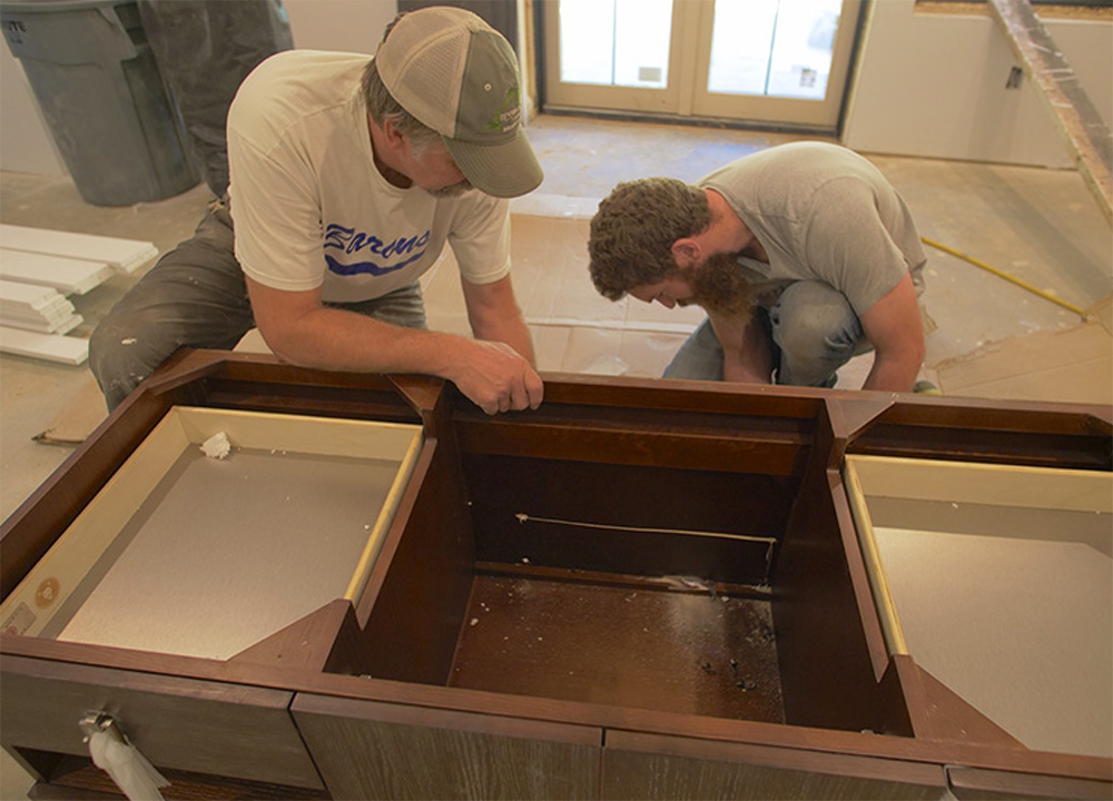 Two men working on a wooden vanity. 