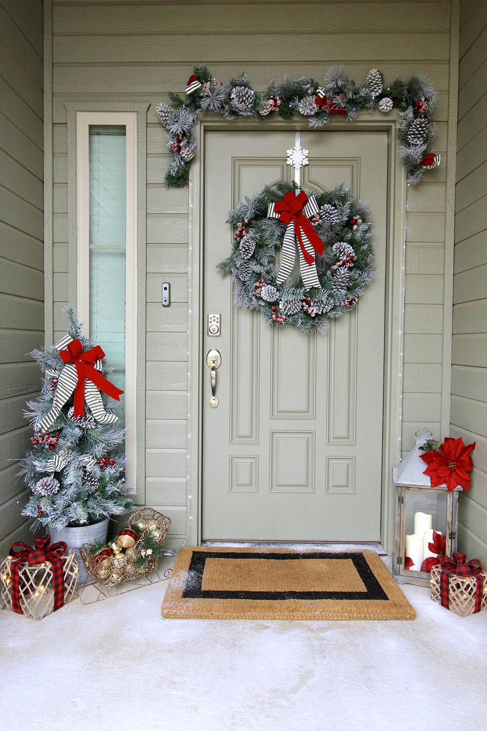 A front entrance decorated for Christmas with a wreath, garland, and an artificial Christmas tree.