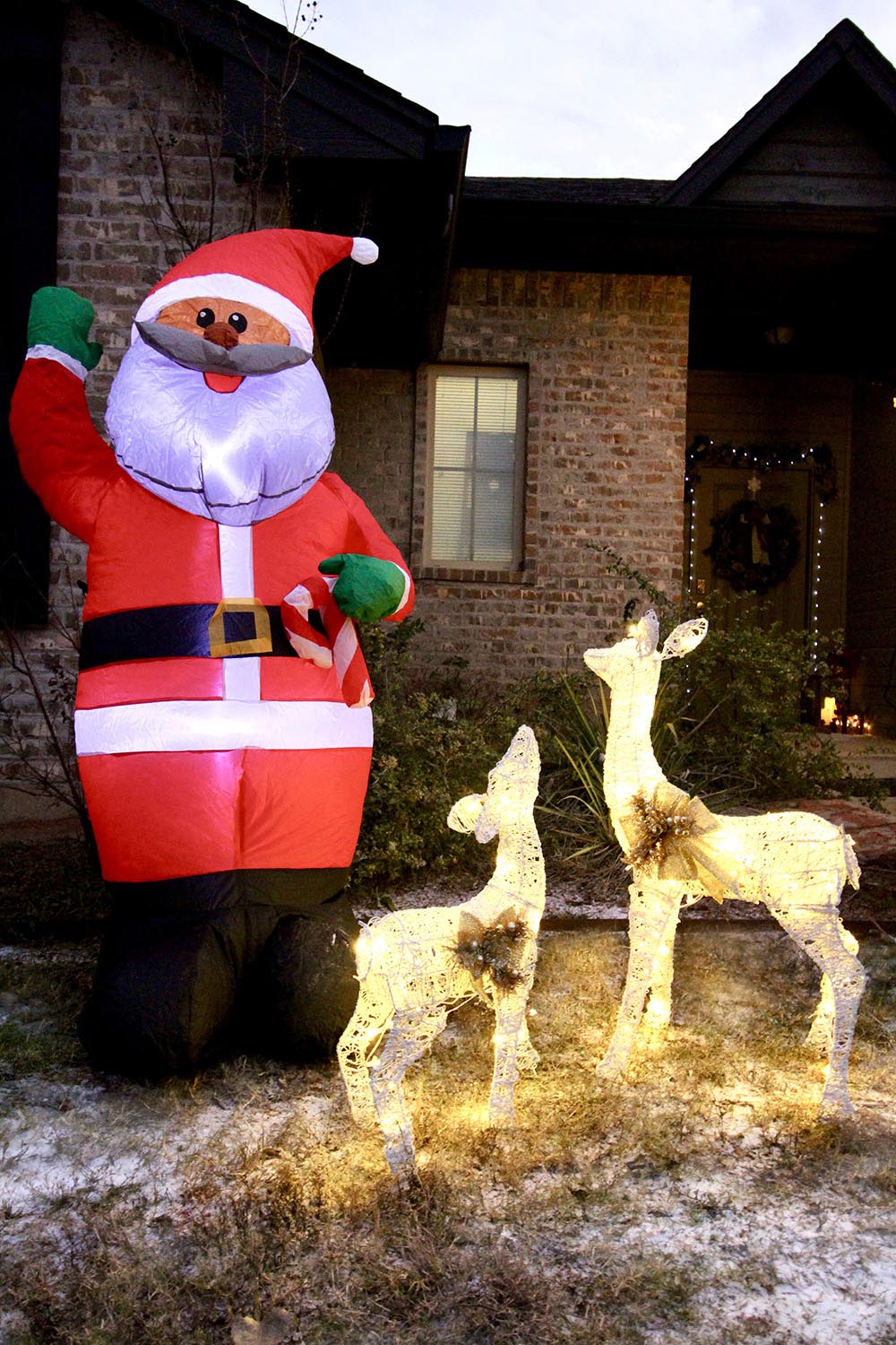 An inflatable ethnic Santa and a pair of lighted deer decorate a yard for Christmas.
