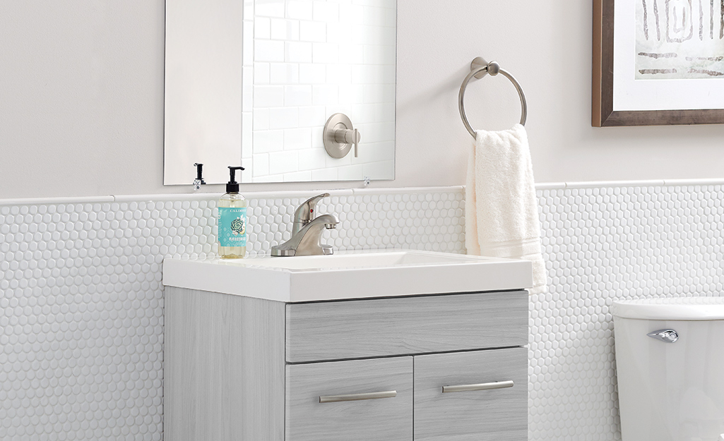A bathroom vanity against a penny tile backsplash.