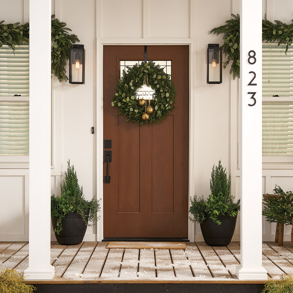 A front door with a wreath made from fresh greenery.