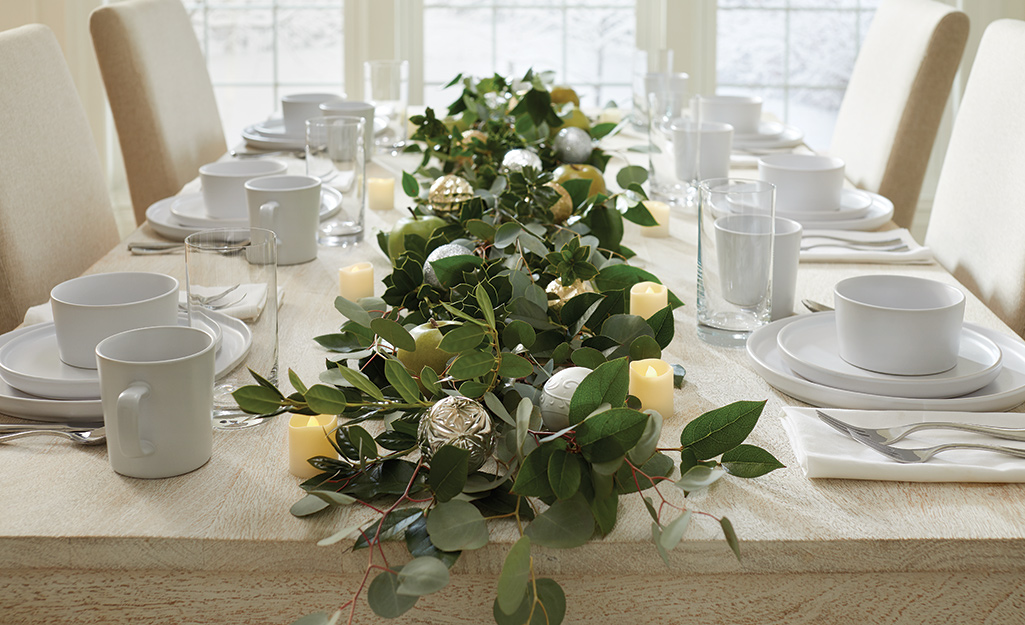 A centerpiece made from different types of fresh greenery and Christmas ornaments.