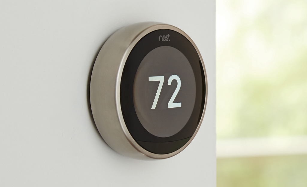 A smart thermostat is installed on a wall.