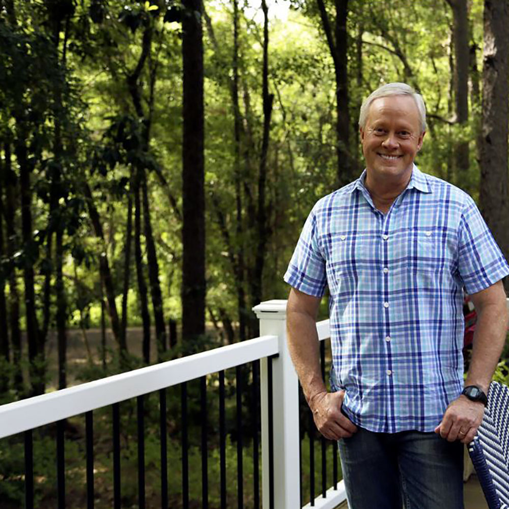 A man standing in front of a black and white fence.