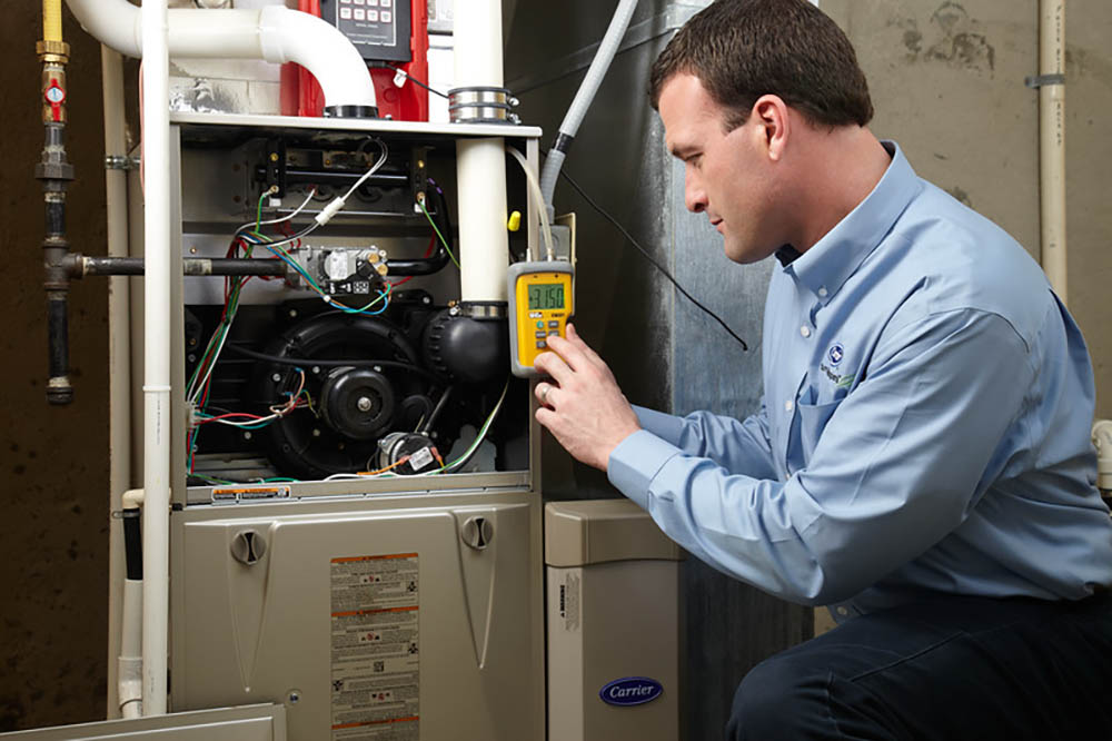 A man inspecting a heating and cooling system with a handheld tool.