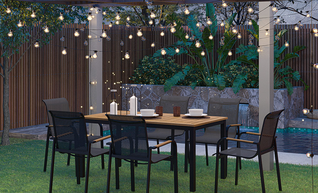 Lights are installed above a patio table with candles and chairs for a festive look.