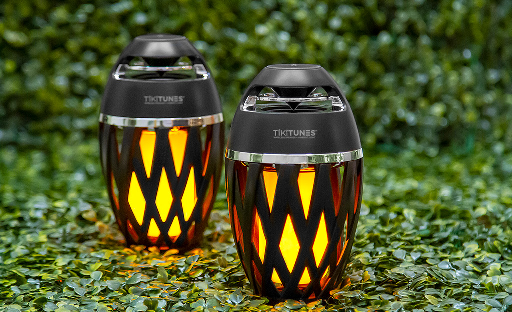 A pair of wireless speakers on a lawn.