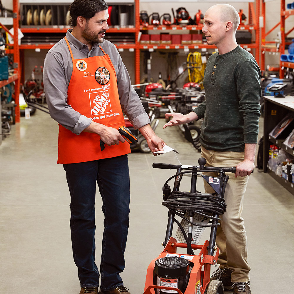 A Home Depot associate helping a customer with a tool rental.