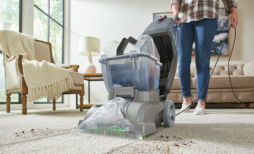 A person using a carpet cleaner in a living room.