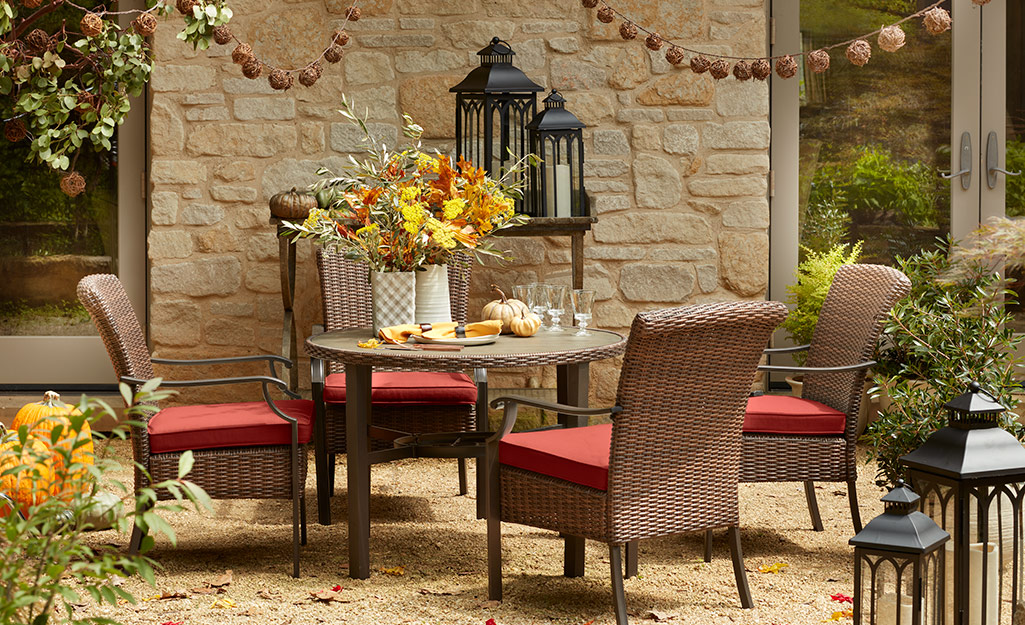 A patio with brick red patio furniture, string lights and fall decor. A patio with brick red patio furniture, string lights and fall decor.