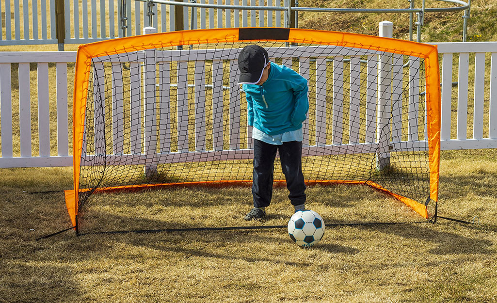 A child plays with a soccer ball in a backyard. 