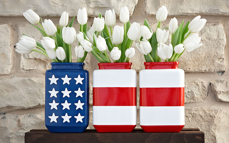 A vase painted blue with white stars sits next to two vases with red and white stripes to look like an American flag.