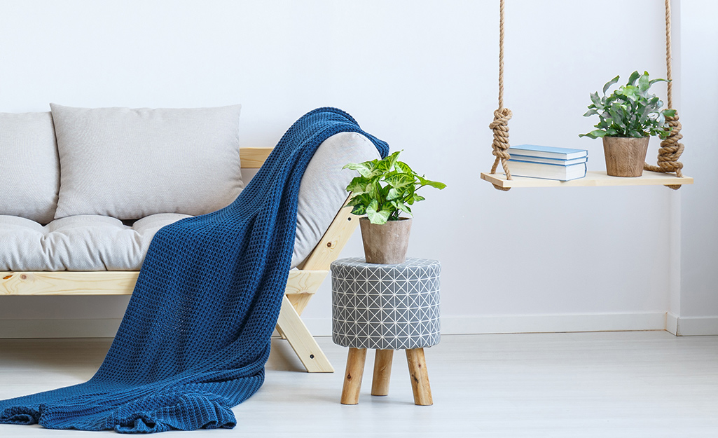 A blue blanket on a white sofa with houseplants