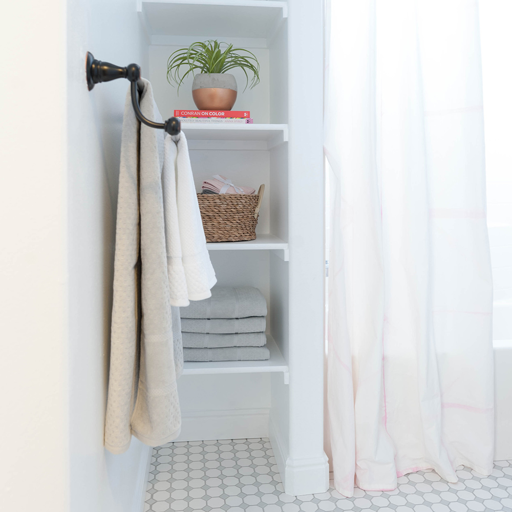A bathroom with white built-in shelving and tile floors.