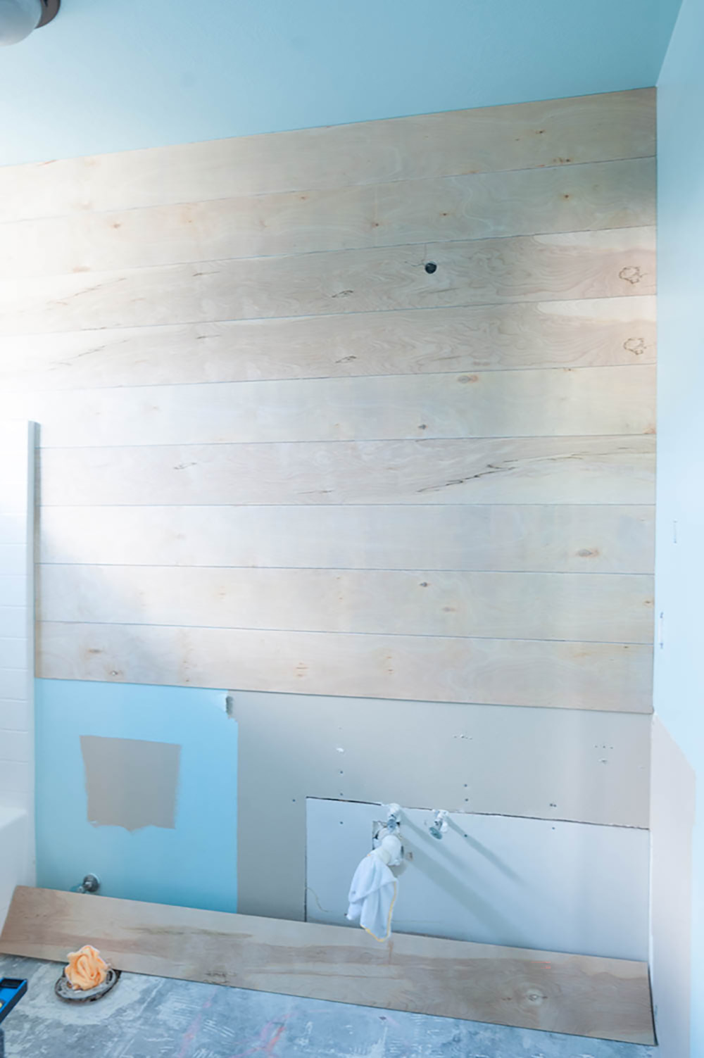 A bathroom wall with shiplap partially installed.