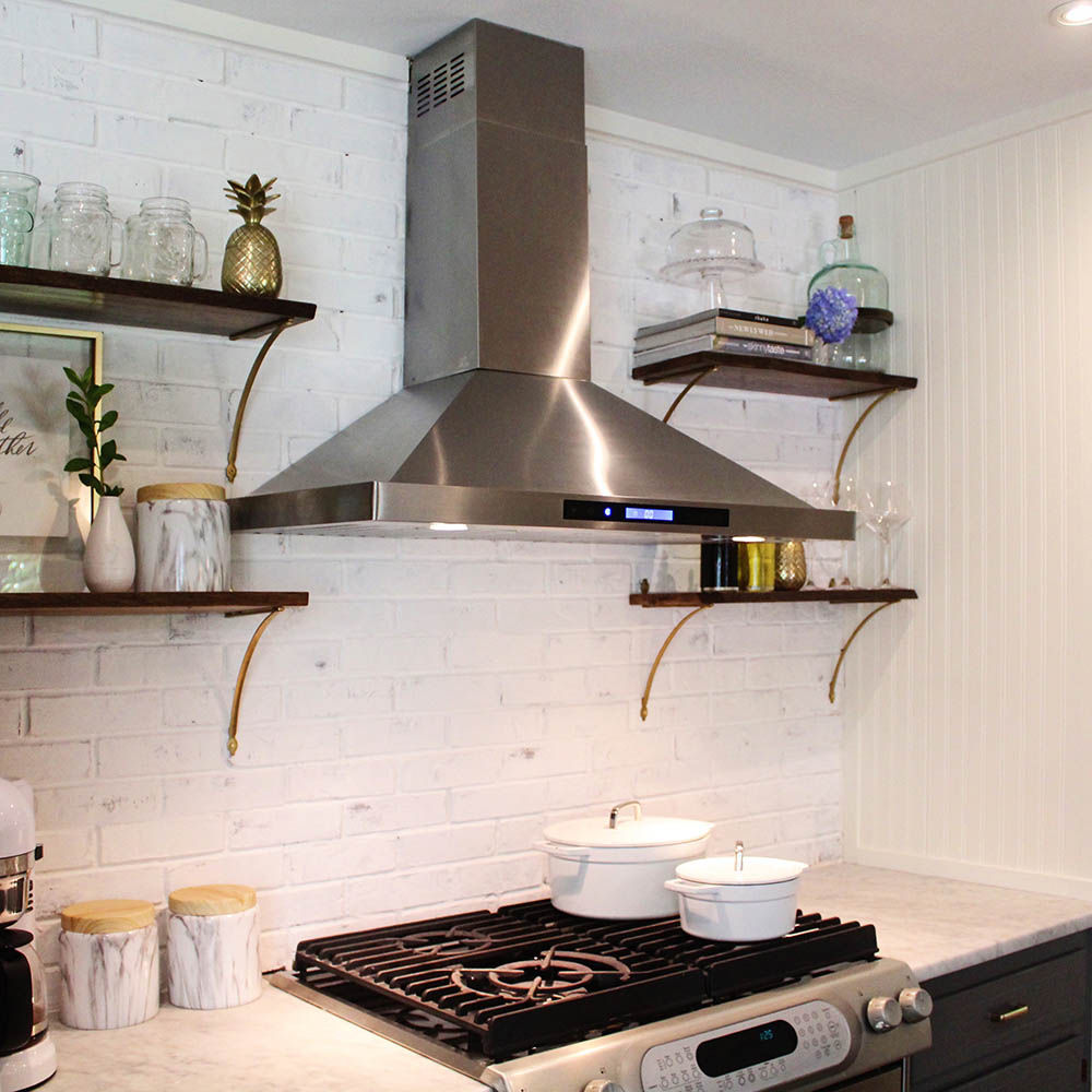 A kitchen wall with a limewashed backsplash and open shelving.