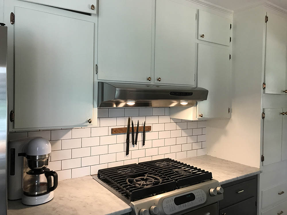 The before of a kitchen with white subway tile and cabinets.