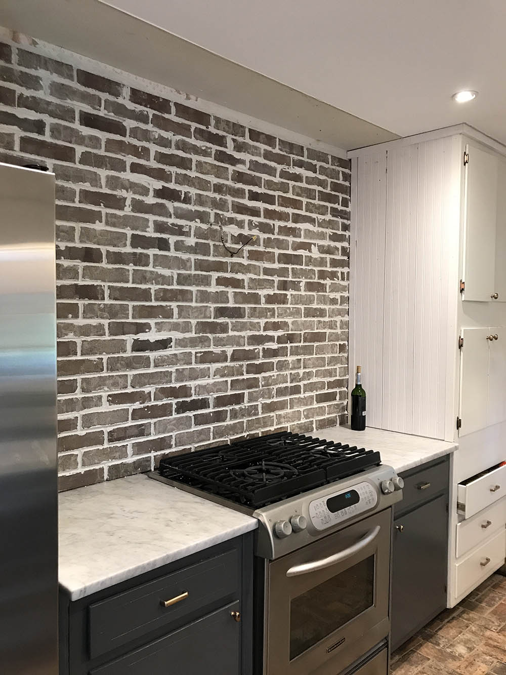 A kitchen wall with a brick tile backsplash.