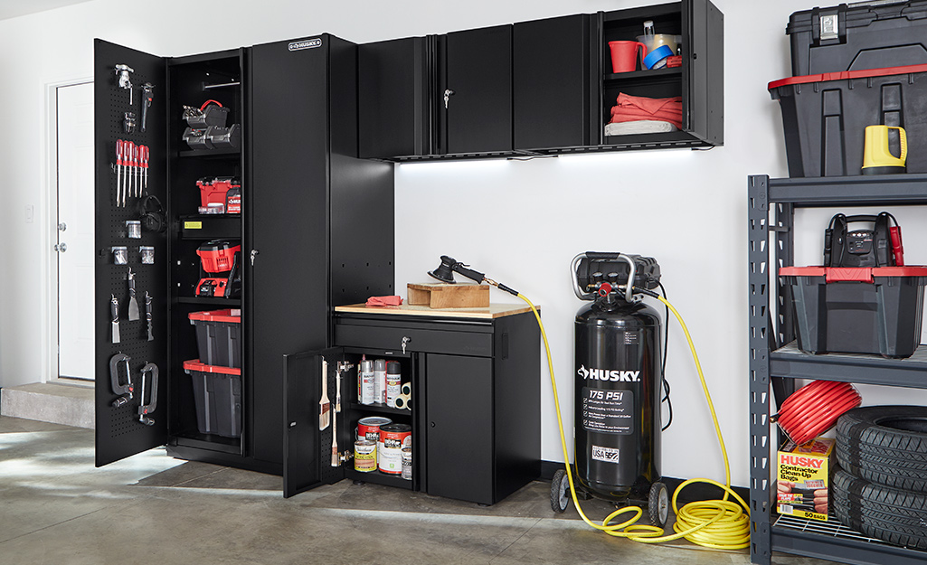 Black cabinets in a garage hold tools and supplies.