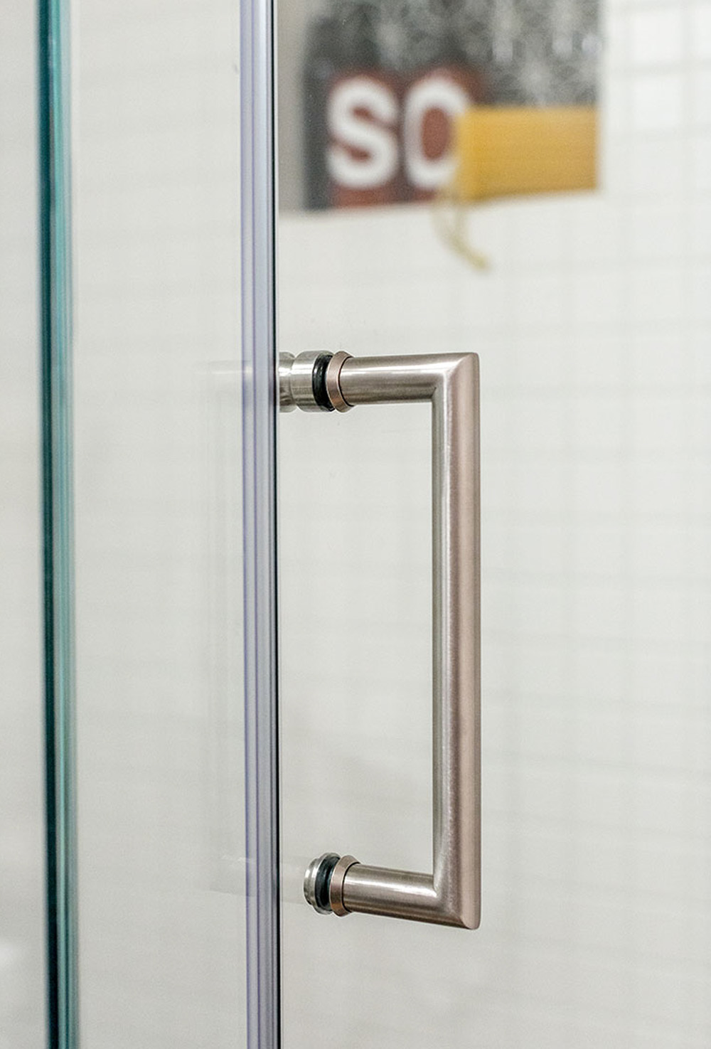 A silver handle on a glass shower door.