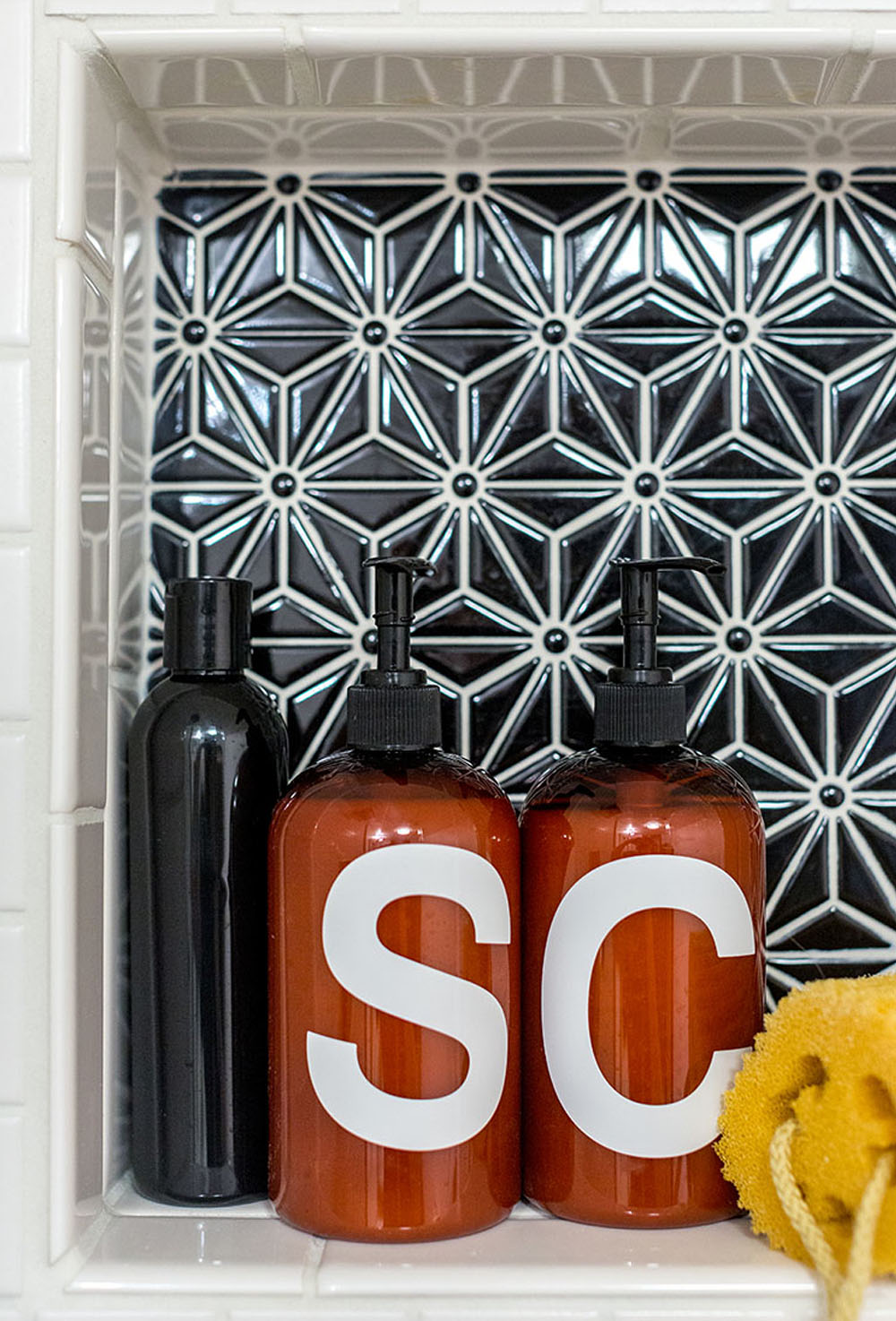 White tiled shower and a shelf with blue tile and shampoo dispensers.