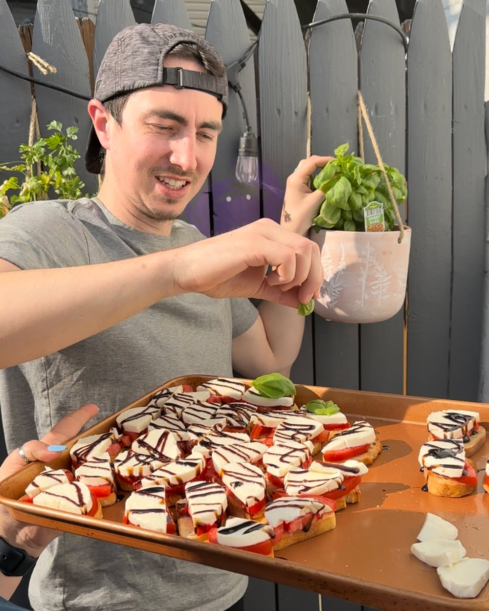 A person topping bruschetta with fresh basil. A person topping bruschetta with fresh basil.