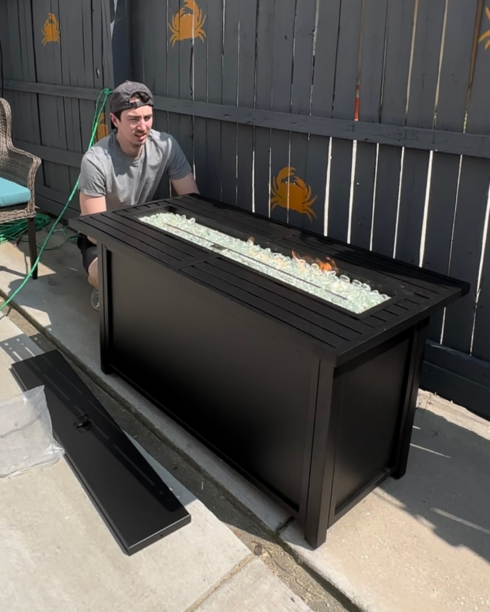 A person moving a electric-starter propane fire pit. A person moving a electric-starter propane fire pit.