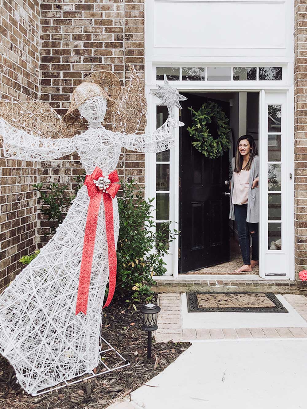 A woman looks out from her decorated front door.