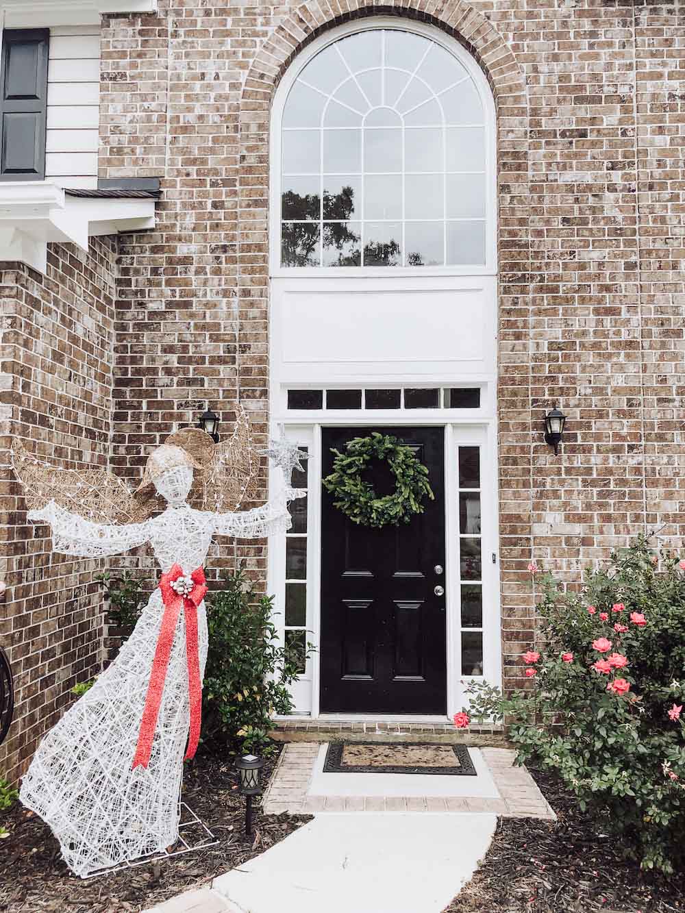 A front porch styled with oversized holiday wreath and decorated LED angel with Star.