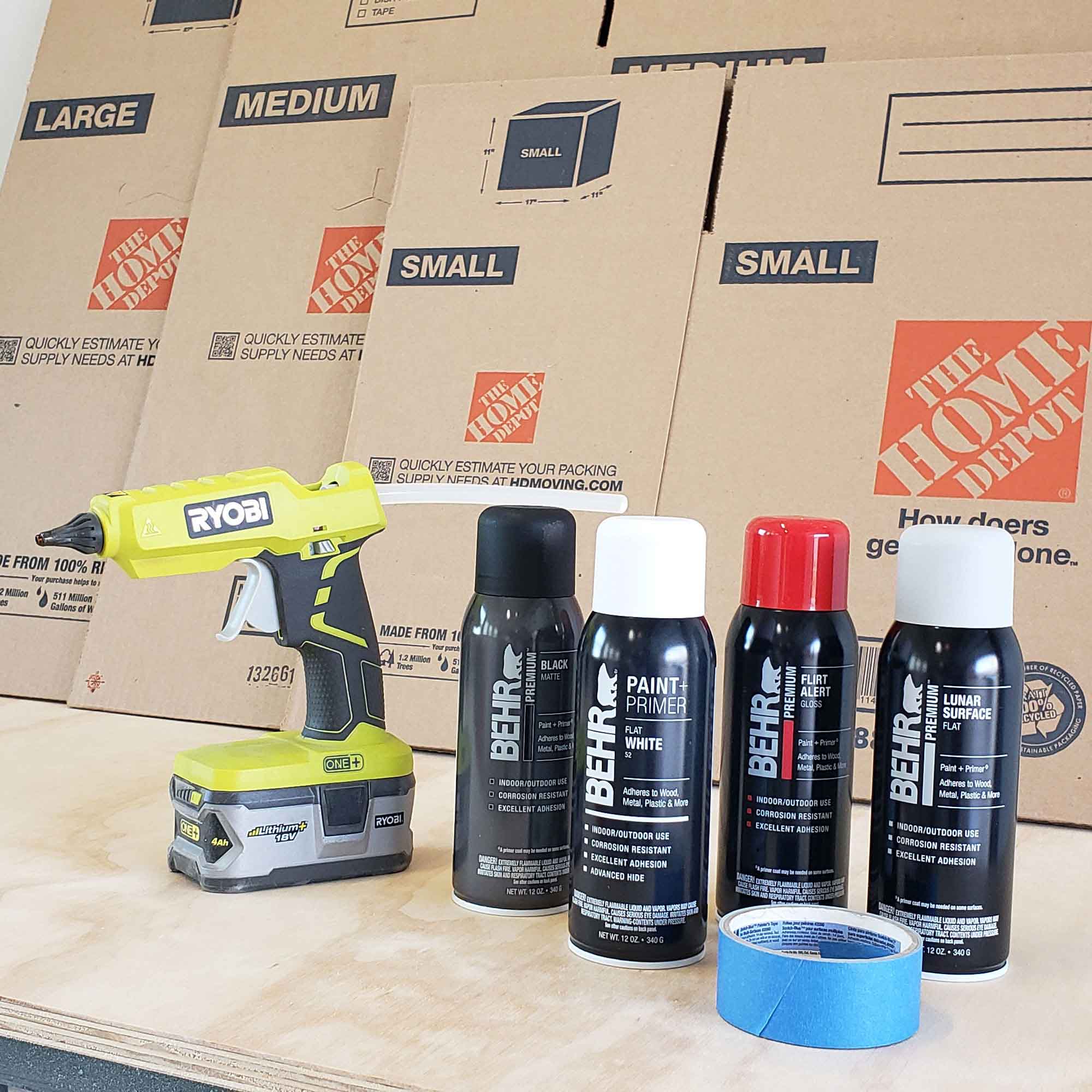 Ryobi hot glue stick next to bottles of spray paint