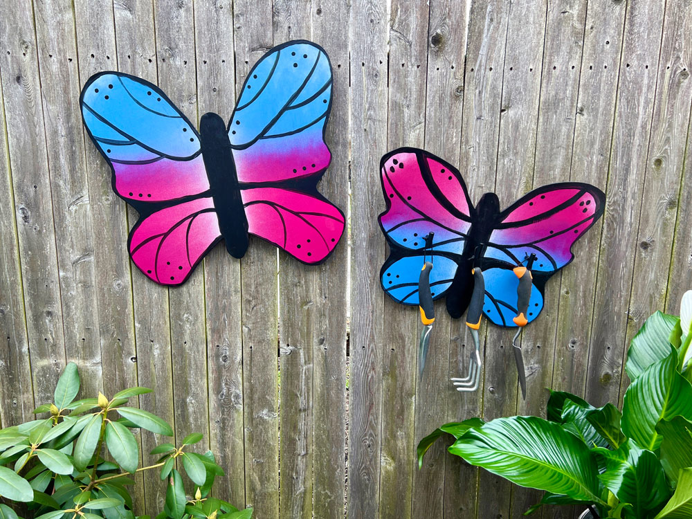 Two magenta and blue butterflies on a wooden fence.