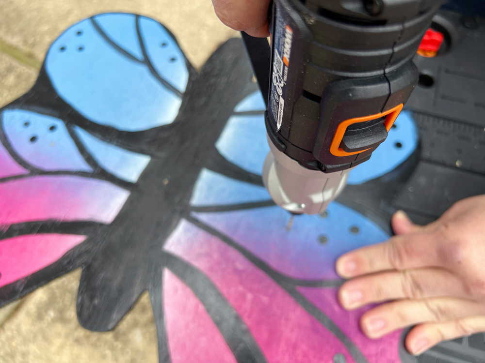 Person drilling holes into the painted butterfly.
