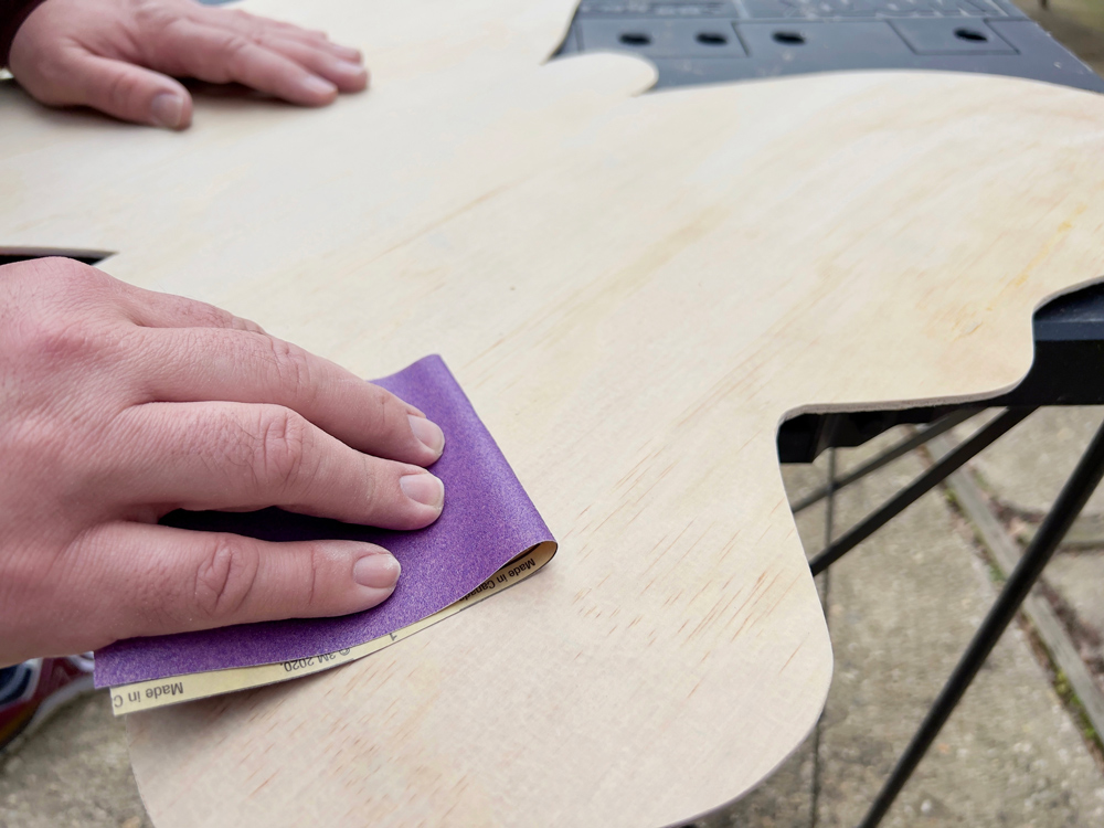 Person sanding down a plywood butterfly.