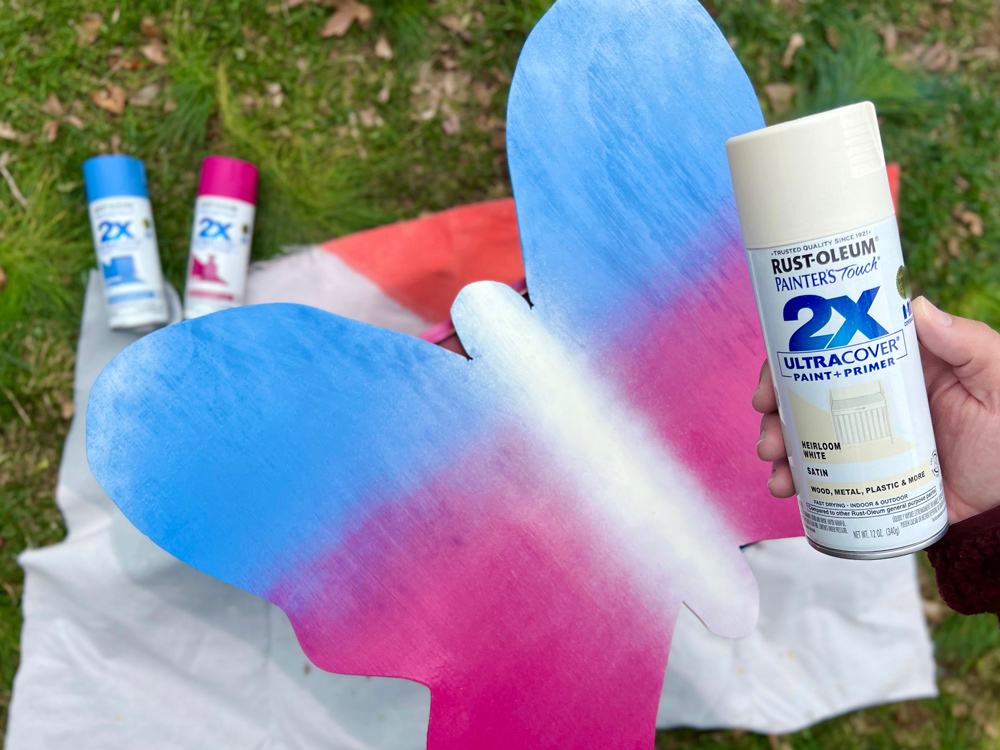 Plywood butterfly spray painted with blue to pink ombre and a white center.