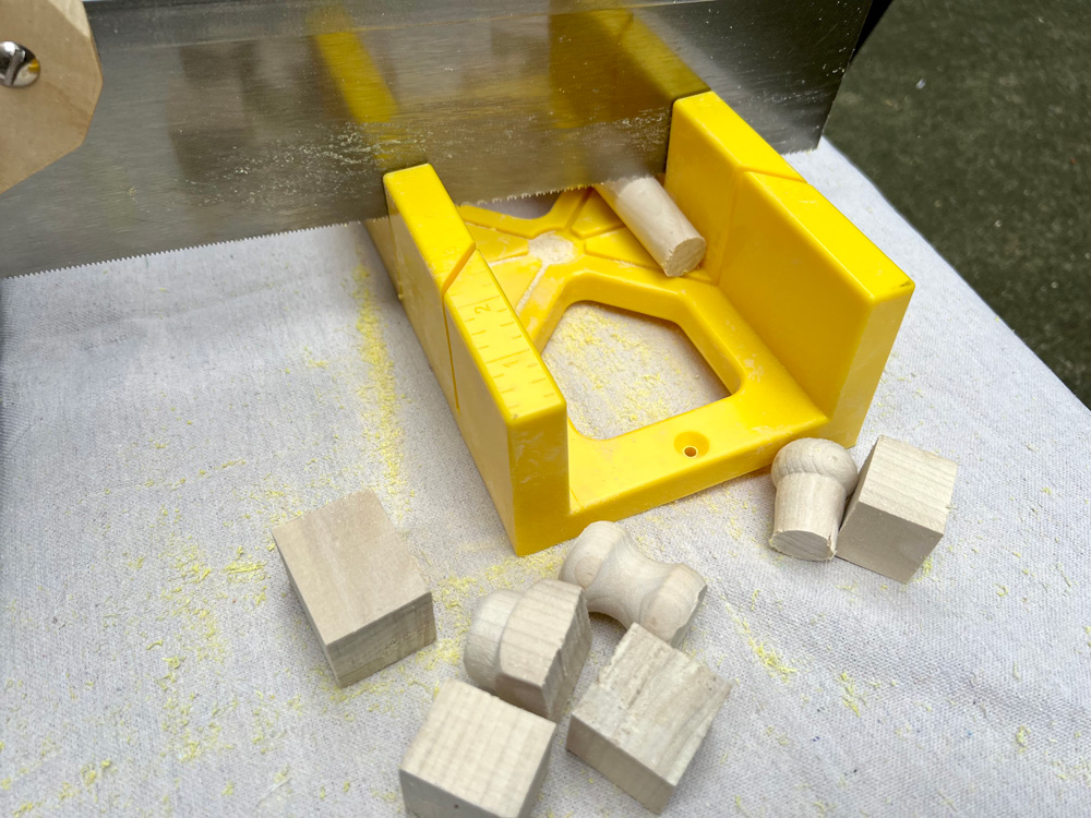 A saw being used on a dowel piece on a yellow sawing guide.