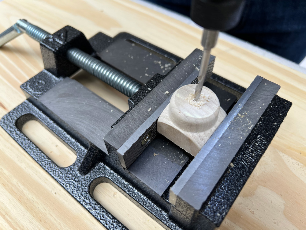 A clamp being used on a spindle while it is being drilled with a drill bit.
