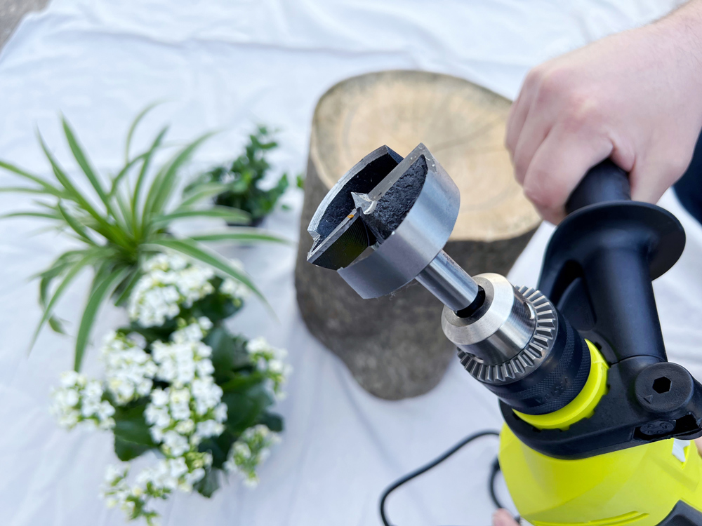 A hand holding a drill with a forstner bit attached. A hand holding a drill with a forstner bit attached.