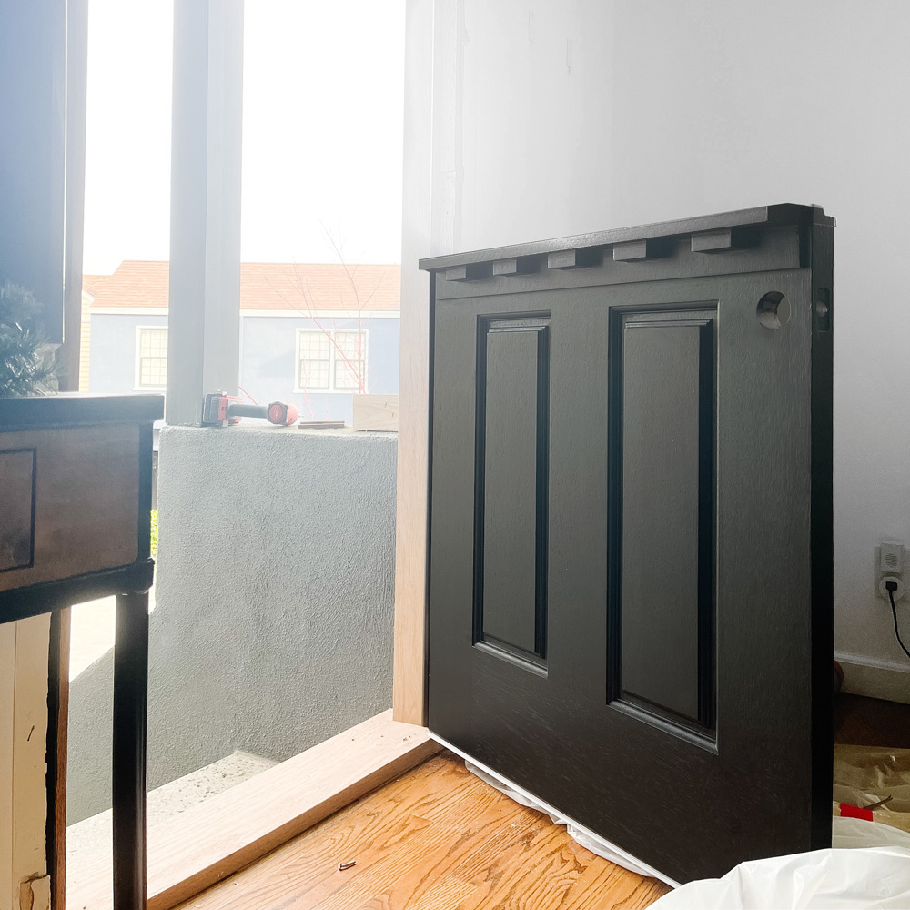 A bottom half of a black Dutch door ajar in a doorway.