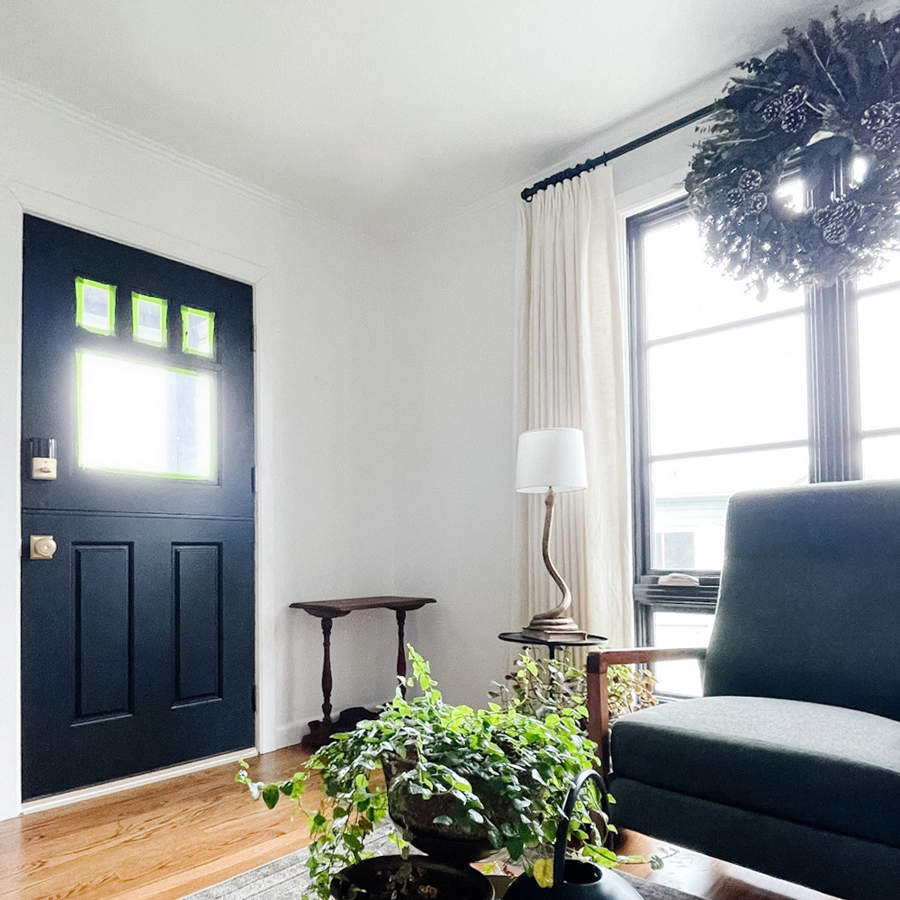 An installed black Dutch door with windows in the entryway of a living room.