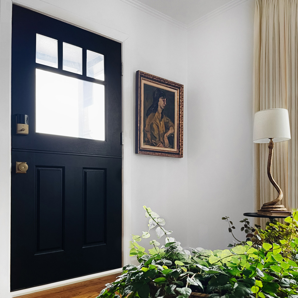 A finished and installed black Dutch door in the doorway of a living room.