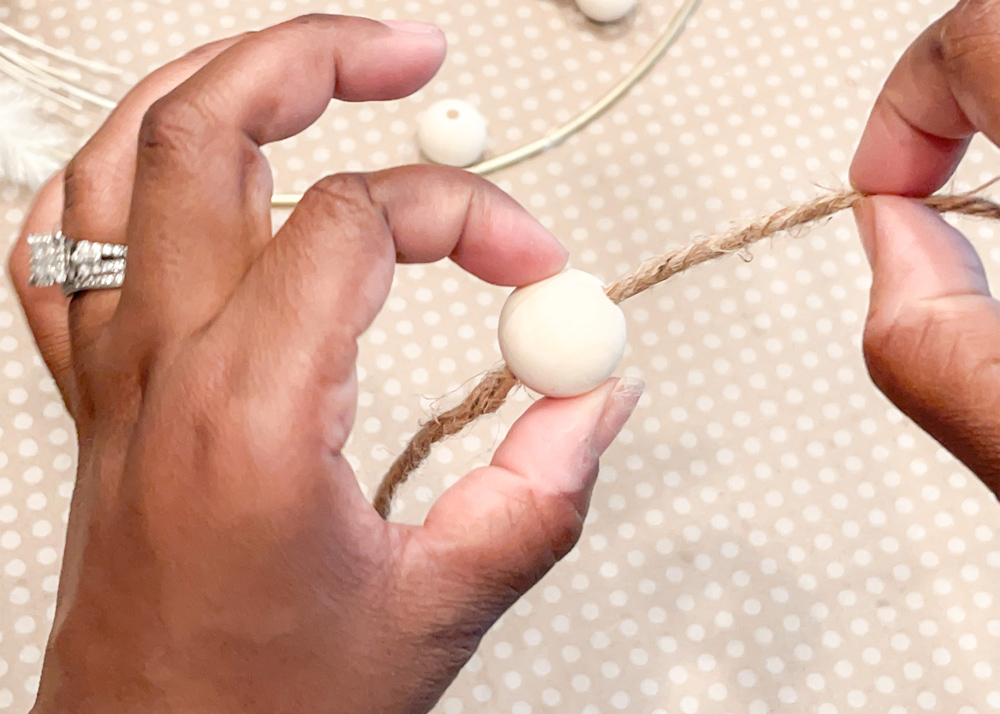 Person adding wooden bead to twine. 