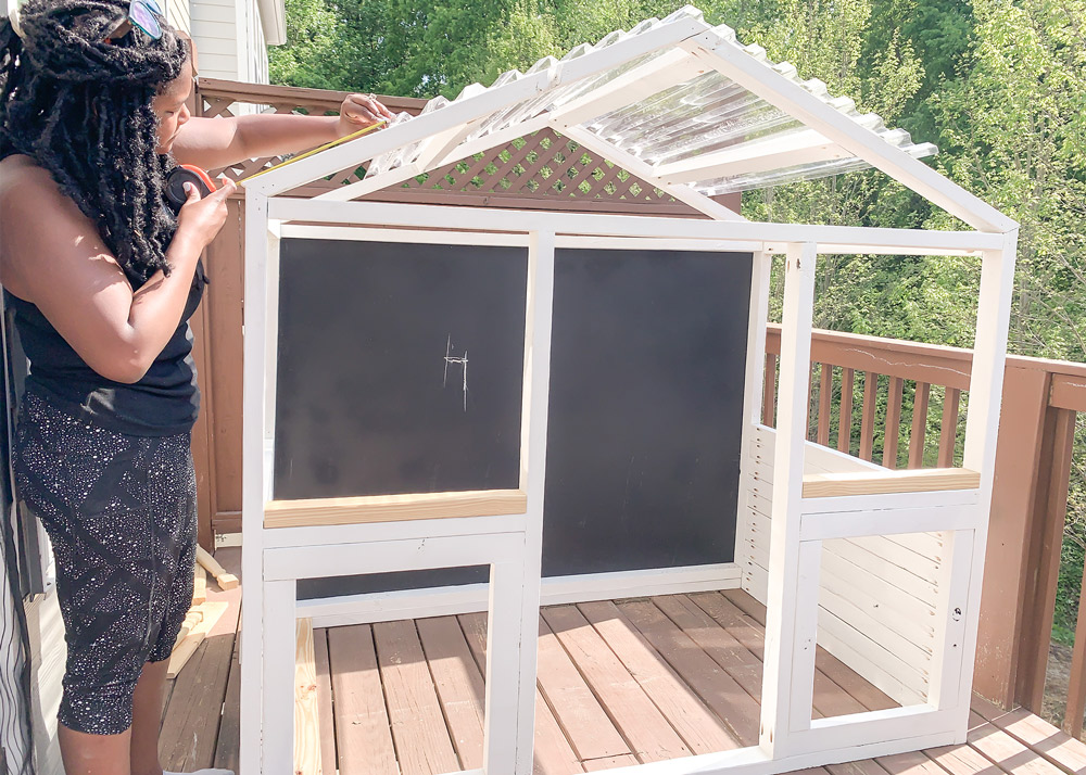 Shot of Ashleigh attaching polycarbonate roofing panel to top of playhouse