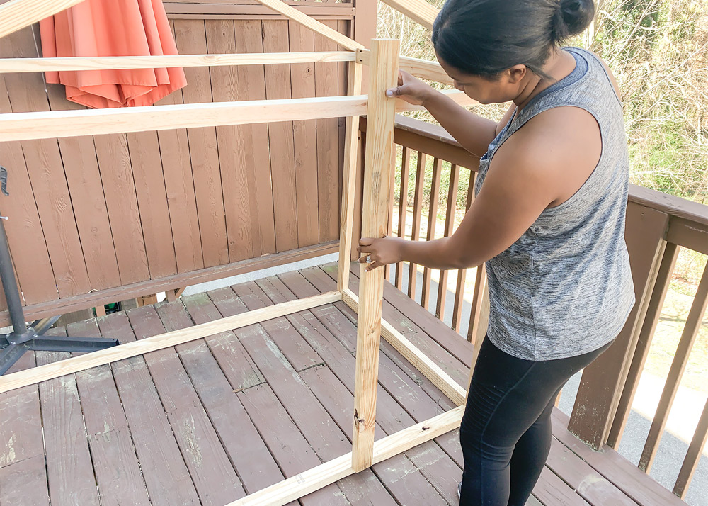 Shot of Ashleigh attaching wood to frame the front of the playhouse